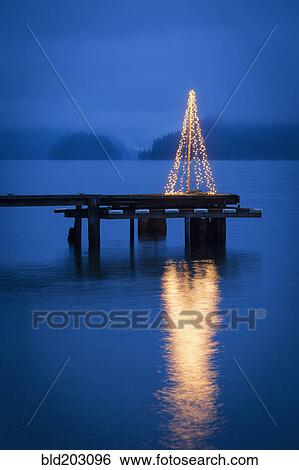 Stock Photograph - String of lights in tree shape on wooden pier. Fotosearch