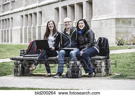 Picture - Students sitting on bench together. Fotosearch