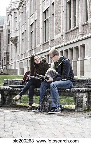 Stock Image - Students sitting on bench together. Fotosearch