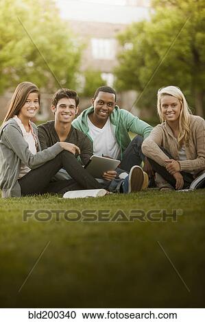 Stock Image - Students sitting together on grass. Fotosearch
