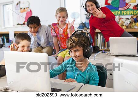 Stock Image - Students using laptops in classroom. Fotosearch