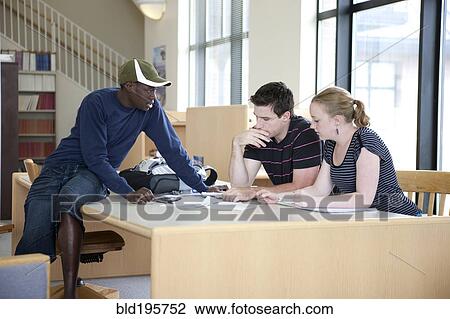 Stock Image - Students working together in library. Fotosearch