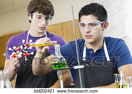 Stock Image - Students working with chemicals in classroom. Fotosearch