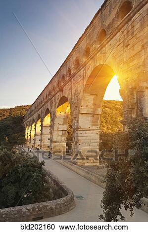 Stock Image - Sun shining through aqueduct. Fotosearch