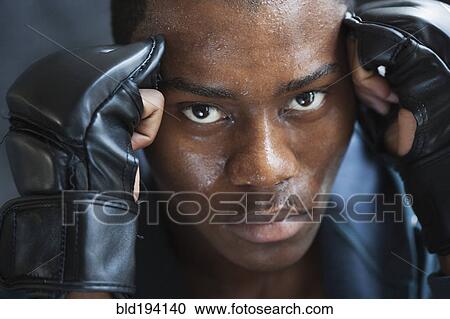 Stock Image - Sweating mixed race man in padded gloves. Fotosearch