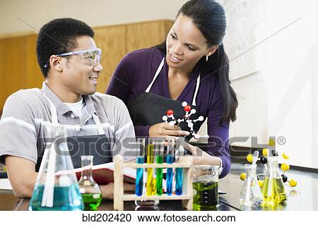 Stock Image - Teacher and student working with chemicals in classroom. Fotosearch