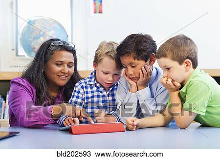 Stock Image - Teacher and students using digital tablet. Fotosearch