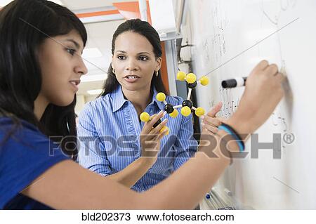 Stock Image - Teacher explaining chemistry model to student. Fotosearch