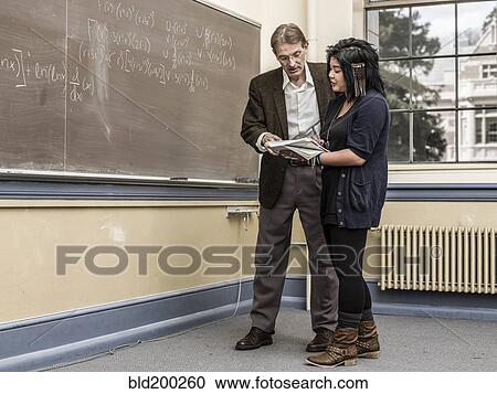 Stock Image - Teacher helping student in classroom. Fotosearch