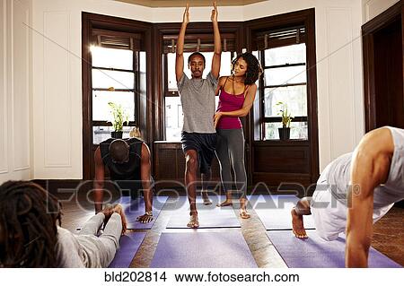 Picture - Teacher helping student in yoga class. Fotosearch