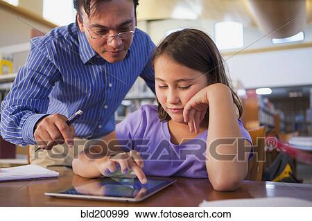 Teacher helping student use digital tablet View Large Photo Image Stock Photo - Teacher helping student use digital tablet. Fotosearch