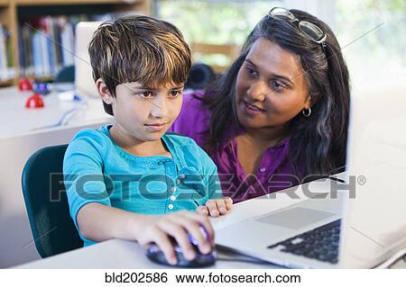 Teacher helping student using laptop View Large Photo Image Stock Photograph - Teacher helping student using laptop. Fotosearch