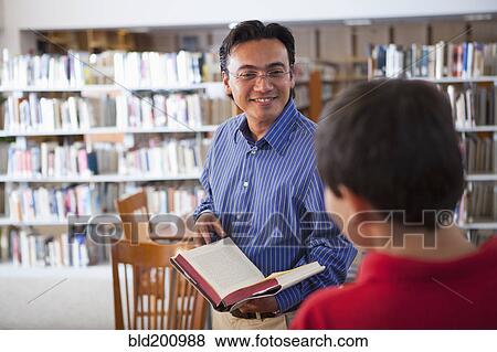 Teacher talking to student in library View Large Photo Image Stock Photo - Teacher talking to student in library. Fotosearch