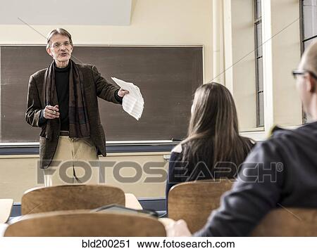 Stock Image - Teacher talking to students in classroom. Fotosearch