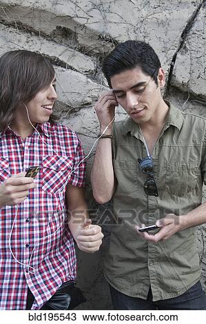 Teenage boys sharing headphones and holding mp3 players View Large Photo Image Stock Image - Teenage boys sharing headphones and holding mp3 players. Fotosearch