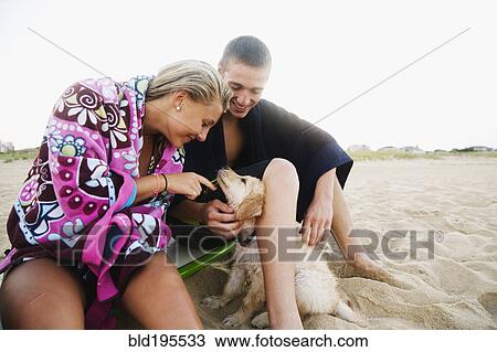 Stock Image - Teenage couple with puppy on beach. Fotosearch