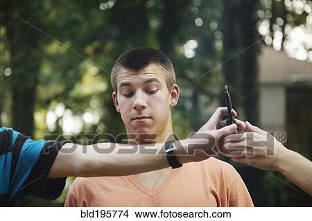 Picture - Teenager watching friends exchange cell phone. Fotosearch