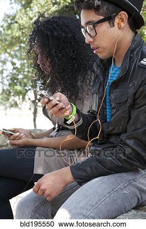Teenagers listening to headphones and mp3 players View Large Photo Image Stock Image - Teenagers listening to headphones and mp3 players. Fotosearch