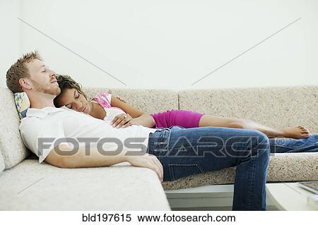 Stock Photography - Tired couple sleeping together on sofa. Fotosearch