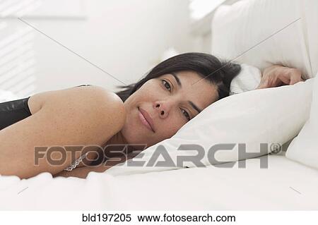 Stock Photography - Tranquil Hispanic woman laying in bed. Fotosearch