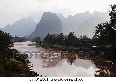 Stock Image - Tranquil river and silhouettes of hills in background. Fotosearch