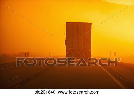 Stock Image - Truck driving down road in dust storm. Fotosearch