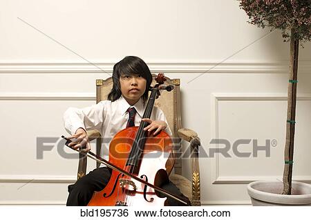 Stock Photograph - Vietnamese boy playing cello on elegant chair. Fotosearch