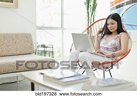 Stock Photo - Vietnamese woman using laptop in living room. Fotosearch