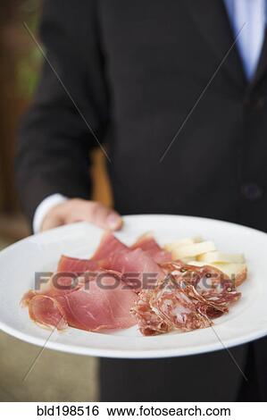 Waiter carrying plate of cured Italian meats View Large Photo Image Stock Photograph - Waiter carrying plate of cured Italian meats. Fotosearch