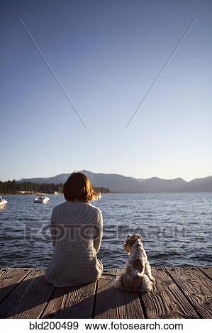 Woman and miniature schnauzer sitting on pier View Large Photo Image Stock Photo - Woman and miniature schnauzer sitting on pier. Fotosearch