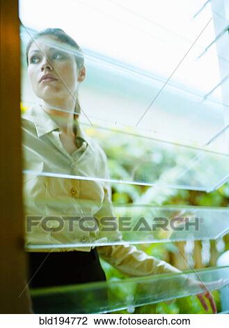 Stock Image - Woman behind window in greenhouse. Fotosearch