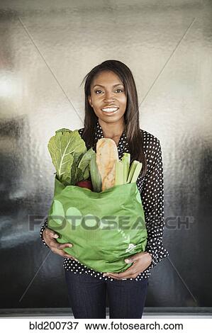 Stock Photo - Woman carrying bag of groceries. Fotosearch