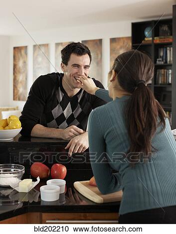 Stock Image - Woman feeding husband in kitchen. Fotosearch