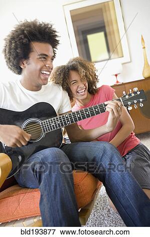 Stock Photo - Woman laughing while boyfriend plays guitar. Fotosearch
