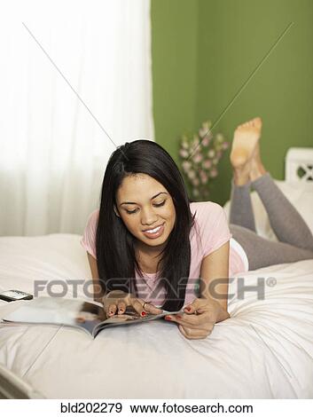 Woman laying in bed reading magazine View Large Photo Image Stock Photo - Woman laying in bed reading magazine. Fotosearch