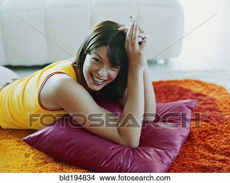 Picture - Woman laying on pillow on floor. Fotosearch
