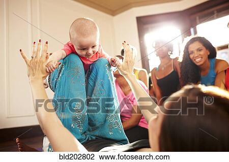 Stock Image - Woman playing with baby on floor. Fotosearch