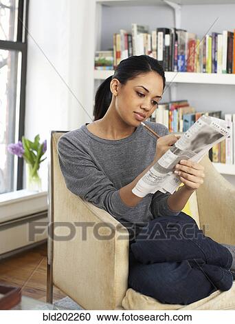 Stock Image - Woman reading classified ads in newspaper. Fotosearch