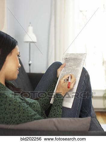 Stock Photograph - Woman reading classified ads in newspaper. Fotosearch