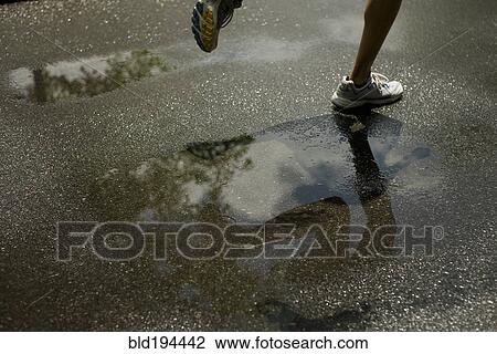 Stock Image - Woman running through puddle. Fotosearch