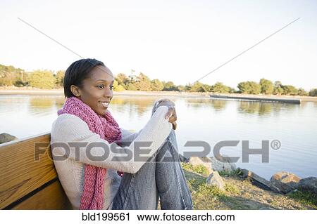 Woman sitting on bench near shore View Large Photo Image Stock Image - Woman sitting on bench near shore. Fotosearch