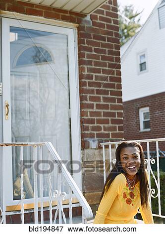 Stock Photo - Woman sitting on front stoop. Fotosearch