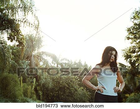 Stock Image - Woman standing outdoors with hands on hips. Fotosearch