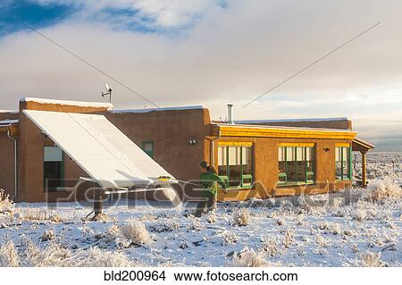 Picture - Woman taking snow off solar panel. Fotosearch