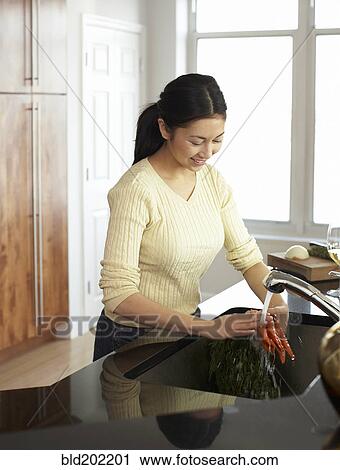 Woman washing carrots in kitchen View Large Photo Image Stock Image - Woman washing carrots in kitchen. Fotosearch