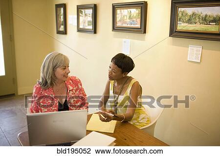 Stock Image - Women in gallery using laptop. Fotosearch
