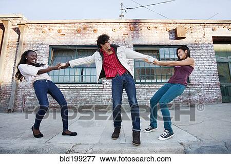 Women pulling on male friend's arms View Large Photo Image Stock Photo - Women pulling on male friend's arms. Fotosearch