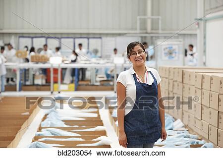 Picture - Worker smiling in manufacturing plant. Fotosearch