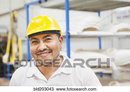 Stock Image - Worker smiling in manufacturing plant. Fotosearch