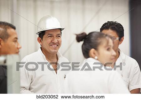 Stock Image - Worker smiling in manufacturing plant. Fotosearch